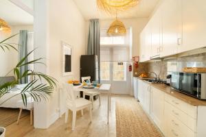 a kitchen with white cabinets and a white table and chairs at Alcácer House in Alcácer do Sal