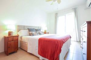 a white bedroom with a large bed with a red blanket at Ap. con vistas panorámicas in Benalmádena
