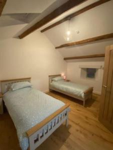 een slaapkamer met 2 bedden in een kamer met houten vloeren bij The Old Shippon, Barbon in Barbon