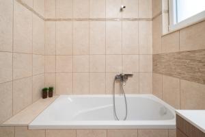 a white bath tub in a tiled bathroom at Nik-Ntin Villa Deluxe in Prinos +27 photos