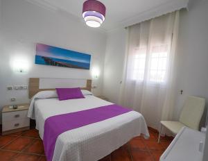 1 dormitorio con 1 cama grande con manta morada en Hostal Los Mellizos, en Conil de la Frontera