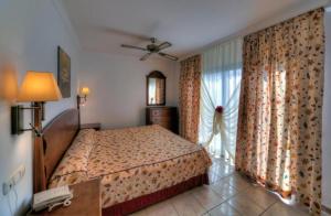 sypialnia z łóżkiem i oknem z zasłonami w obiekcie Las Marismas de Corralejo w Corralejo