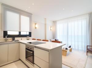 a kitchen with white appliances and a living room at LIV Mackenzie Beach Suites Larnaca ADULTS ONLY in Larnaka