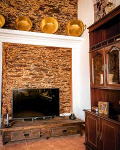 a living room with a large television on a brick wall at Monte da Parreira in Cabeça de Carneiro