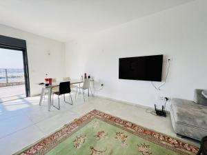 Luxury Penthouse 5 Rooms في Or Yehuda: غرفة معيشة مع أريكة وتلفزيون على الحائط