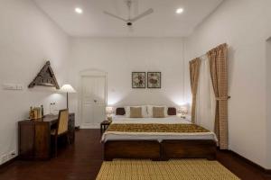 ein Schlafzimmer mit einem großen Bett und einem Schreibtisch darin in der Unterkunft amã Stays & Trails Victory Dawn, Kochi in Fort Kochi
