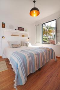 a white bedroom with a large bed and a window at Casa das Rosas by Homing in Arco da Calheta