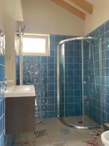 uma casa de banho em azulejos azuis com um chuveiro e um lavatório. em Nuver Plekkie em Yde