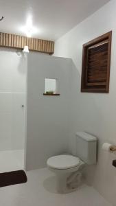 a white bathroom with a toilet and a window at Casa Serena in Atins