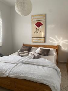 um quarto com uma cama com lençóis brancos e uma flor vermelha em Apartman Matošević em Poreč