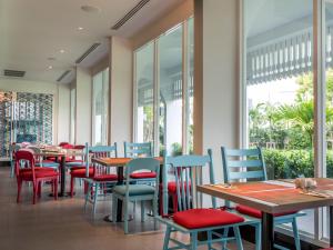 a restaurant with tables and chairs and windows at Ibis Styles Phuket City in Phuket Town
