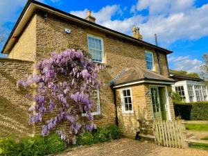 una casa de ladrillo con un arbusto púrpura delante de ella en Station House, Gilling en Gilling East