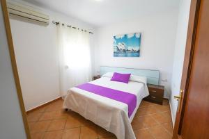 a bedroom with a bed with a purple pillow at Apartamentos Los Mellizos in Conil de la Frontera