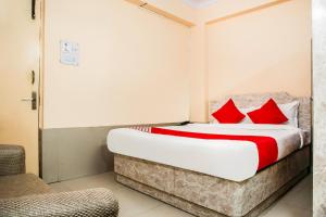 ein Schlafzimmer mit einem Bett mit roten Kissen und einem Stuhl in der Unterkunft Flagship Hotel Embassy Exhibition Rd in Patna