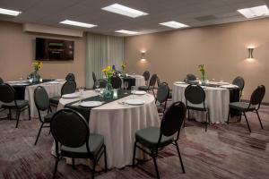 d'une salle de conférence avec des tables et des chaises et des fleurs. dans l'établissement Courtyard by Marriott Mt. Laurel, à Mount Laurel