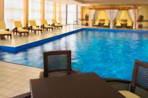 uma grande piscina num hotel com cadeiras e mesas em Detroit Marriott Troy em Troy