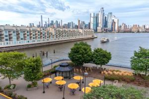 a group of tables with yellow umbrellas in front of a city at Sheraton Lincoln Harbor Hotel in Weehawken