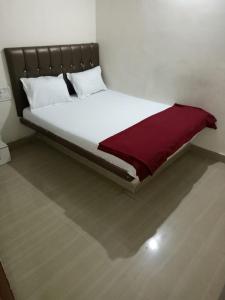a white bed with a red blanket on top of it at Hotel janata Residency in Mumbai