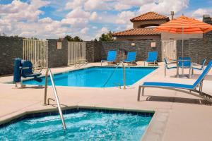 a swimming pool with chairs and an umbrella at TownePlace Suites by Marriott Albuquerque Airport in Albuquerque