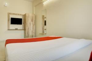 a bedroom with a bed and a tv on the wall at OYO Aditya Service Apartment in Méribel Village