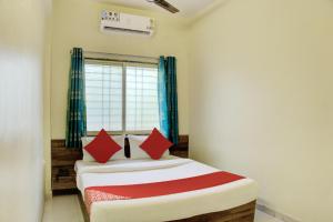 a bedroom with a bed with red pillows and a window at OYO Aditya Service Apartment in Méribel Village