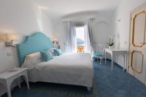 a bedroom with a large bed with blue pillows at Hotel Conca d'Oro in Positano