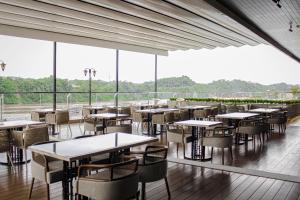 a restaurant with tables and chairs and large windows at HARRIS Hotel Samarinda in Samarinda