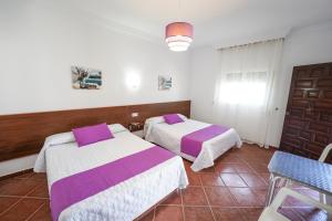 a bedroom with two beds and a table and a window at Apartamentos Los Mellizos in Conil de la Frontera