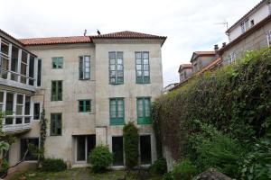 un antiguo edificio de piedra con ventanas verdes y un seto en -MORC-beds & rooms-(home sharing)-, en Pontevedra