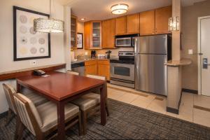a kitchen with a wooden table and a stainless steel refrigerator at Residence Inn Dulles Airport At Dulles 28 Centre in Sterling