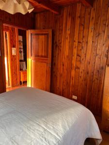 una camera con pareti in legno e un letto in una stanza di hermosa cabaña a San Carlos de Bariloche