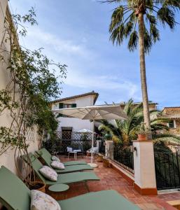 eine Terrasse mit Stühlen, einem Sonnenschirm und Palmen in der Unterkunft Can Abril in Sóller