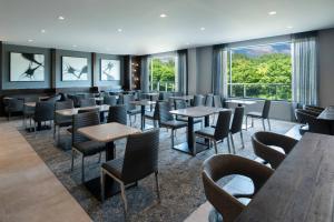 un restaurante con mesas, sillas y ventanas en TownePlace Suites by Marriott Boston Medford, en Medford