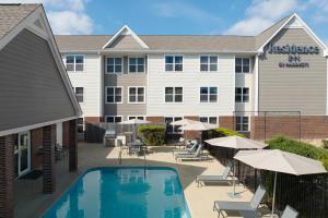 a hotel with a pool and chairs and umbrellas at Residence Inn Austin South in Austin