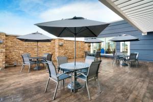 eine Terrasse mit Tischen, Stühlen und Sonnenschirmen in der Unterkunft Fairfield by Marriott Inn & Suites Laurel in Laurel