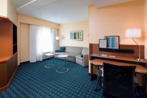 ein Wohnzimmer mit einem Sofa und einem Schreibtisch in einem Hotelzimmer in der Unterkunft Fairfield Inn & Suites by Marriott Newark Liberty International Airport in Newark