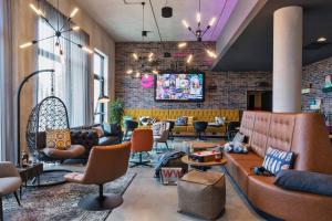 a lobby with couches and chairs and a tv at Moxy Frankfurt Airport Kelsterbach in Kelsterbach