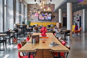 a restaurant with a large wooden table and chairs at Moxy Frankfurt Airport Kelsterbach in Kelsterbach