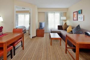 Residence Inn Houston Sugar Land/Stafford في ستافورد: غرفة معيشة مع أريكة وغرفة مع سرير