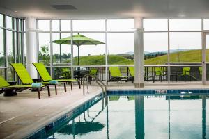 - une piscine avec des chaises, une table et un parasol dans l'établissement SpringHill Suites by Marriott Kalispell, à Kalispell