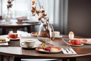 a table with plates of food and a vase with flowers at AC Hotel Huelva by Marriott in Huelva