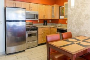 Residence Inn Sioux Falls في شلالات سيوكس: مطبخ مع ثلاجة ستانلس ستيل وطاولة