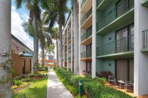 un edificio de apartamentos con palmeras y una acera en Courtyard by Marriott Fort Lauderdale East / Lauderdale-by-the-Sea en Fort Lauderdale