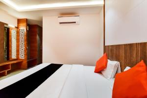 1 dormitorio con cama blanca y almohadas de color naranja en Maurya Inn en Jodhpur