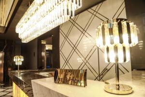 a lobby with two chandeliers and a sign on a counter at Iris Hotel Baku - Halal Hotel in Baku