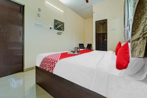 een slaapkamer met een groot wit bed met rode kussens bij Hotel Everest Grand in Coimbatore