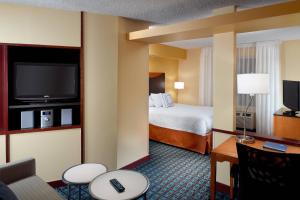 a hotel room with a bed and a flat screen tv at Fairfield Inn & Suites Clarksville in Clarksville