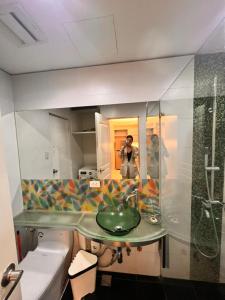 una persona que toma una foto en un espejo de baño en The Pearl Interior Designed 1 BR Unit Burgos Circle BGC en Manila