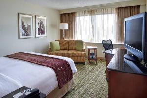 a hotel room with a bed and a flat screen tv at Detroit Marriott Livonia in Livonia