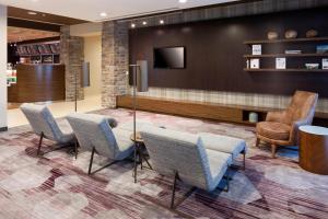 a waiting room with chairs and a table and a tv at Courtyard by Marriott Fort Worth Alliance Town Center in Fort Worth